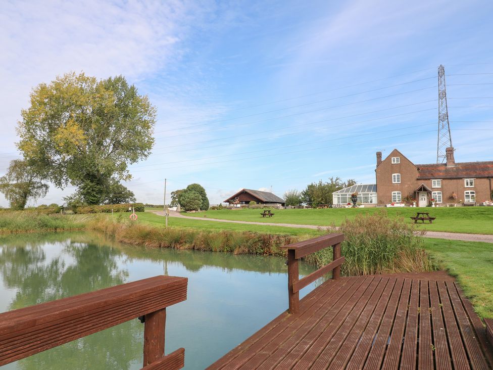 A pond with a deck and building at Far Coley Farm and Kilnhurst Log Cabin in Great Haywood