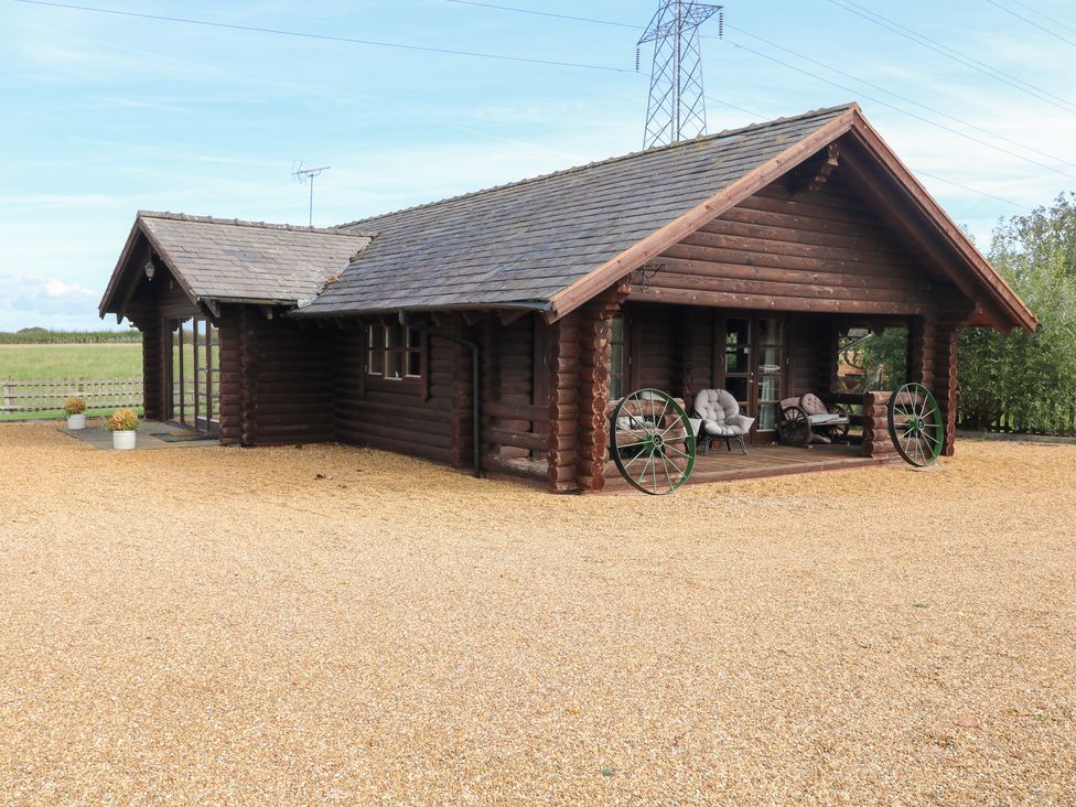 A log cabin with a porch and wheel decorations at Far Coley Farm and Kilnhurst Log Cabin Great Haywood