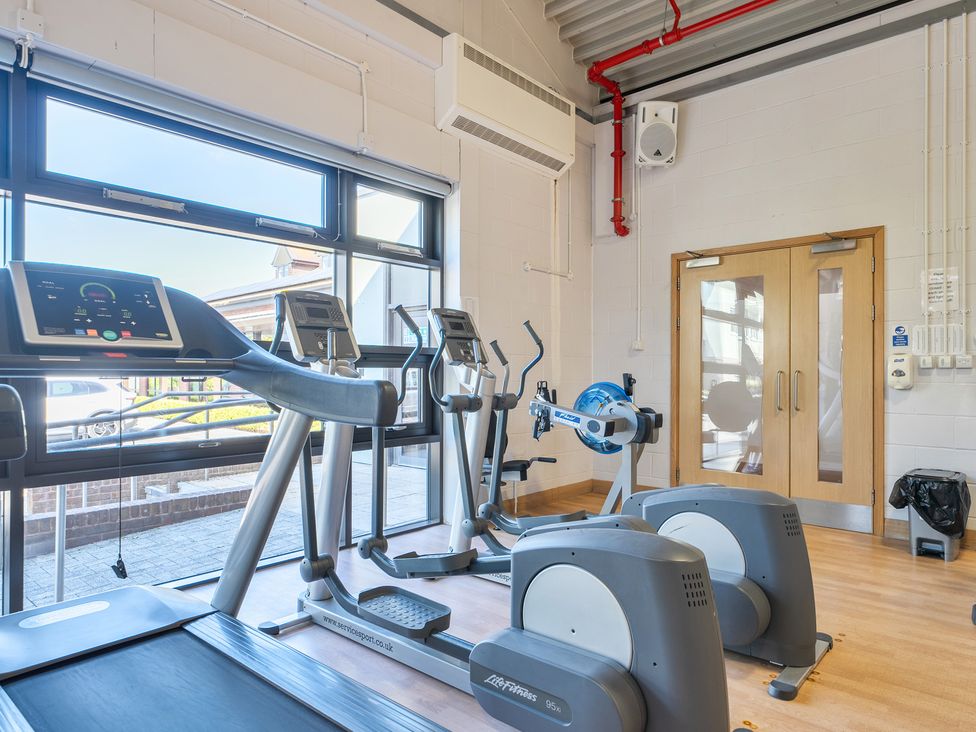 A gym with exercise equipment including a treadmill and elliptical at Marine Court Three Bedroom Second-floor Apartment 32 in Littlehampton