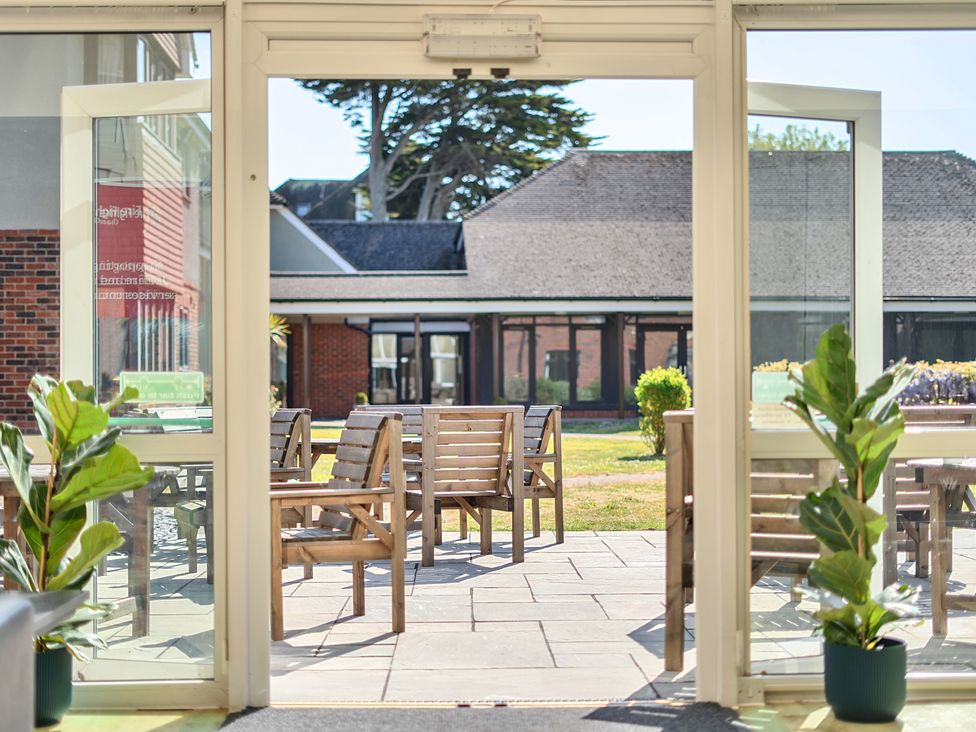 An outdoor area with chairs and a table seen through double doors at Marine Court Two Bedroom Second-floor Apartment 33, Littlehampton