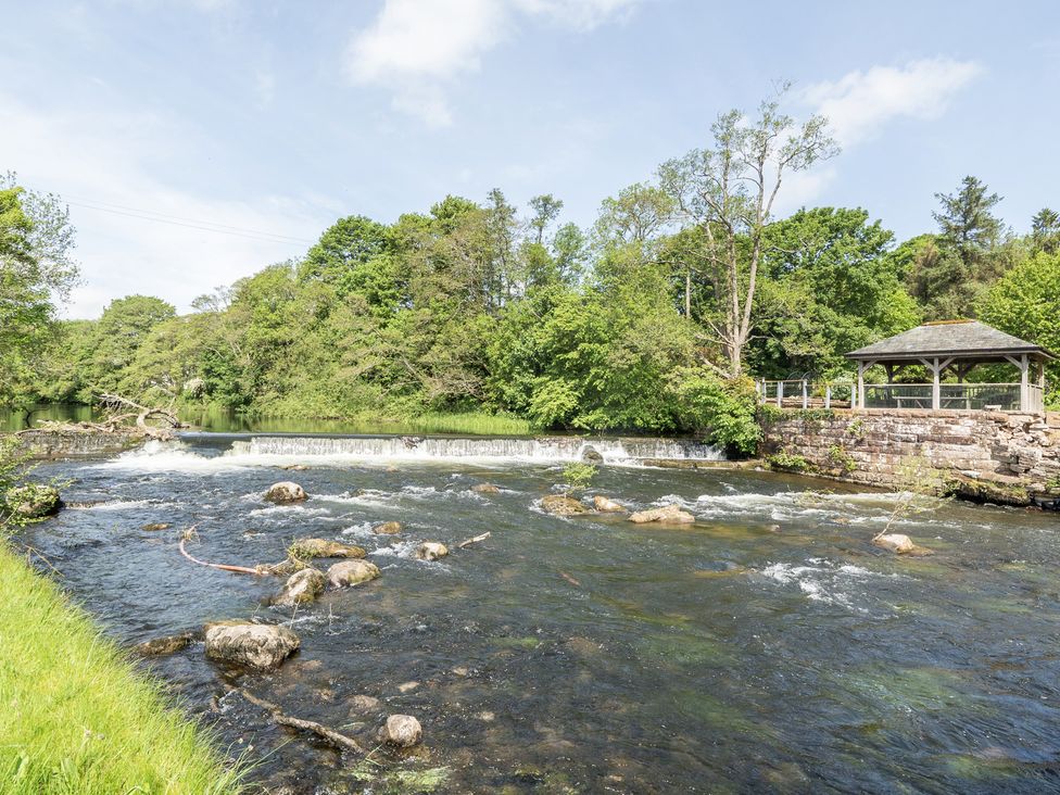 A river with rocks and a gazebo on the bank at Jubilee Two Bedroom House Pet Friendly in Penrith