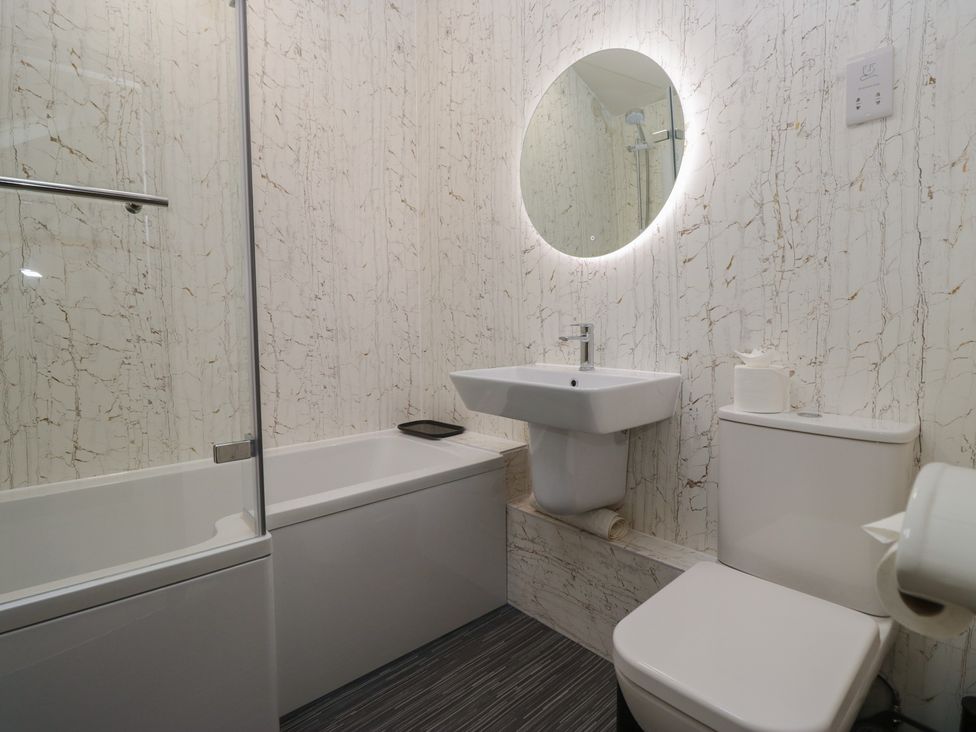 A bathroom with a bathtub, wash basin, and toilet at Cringol Cottage in Ambleside