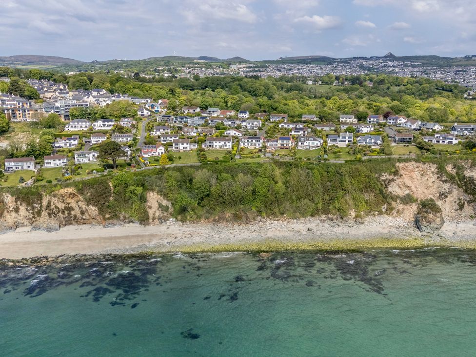 An aerial view of houses on a cliff near the ocean at 7 Duporth Bay in St. Austell
