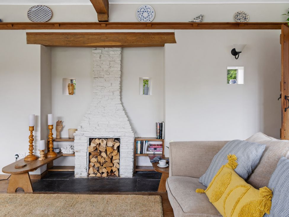 A living room featuring a fireplace with wood logs and a sofa at 7 Duporth Bay in St. Austell