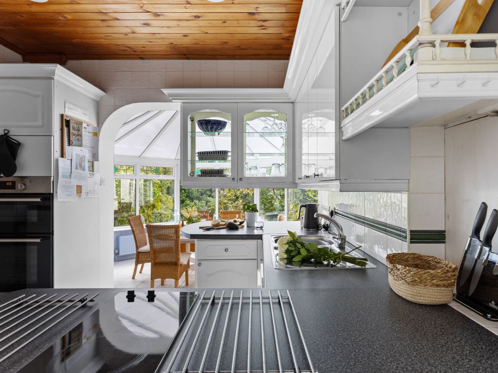 A kitchen with a sink, counter, and chairs at 7 Duporth Bay in St. Austell
