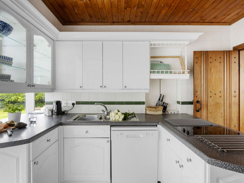 A kitchen with cabinets, countertop, sink, and potted plants at 7 Duporth Bay, St. Austell