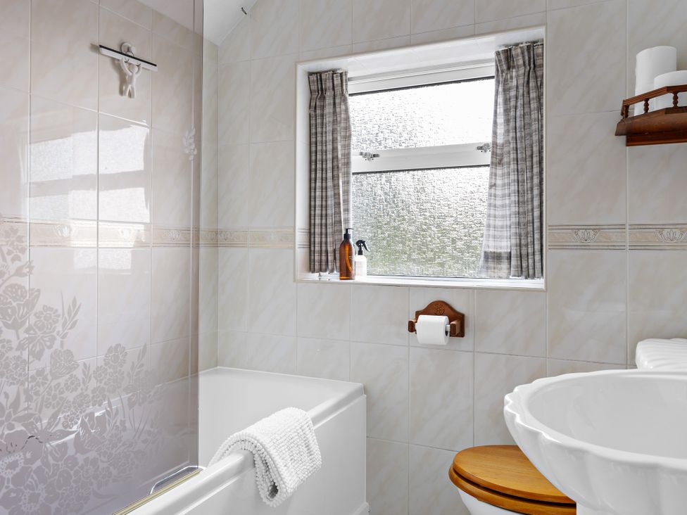 A bathroom with a bathtub, toilet, and sink at 7 Duporth Bay in St. Austell