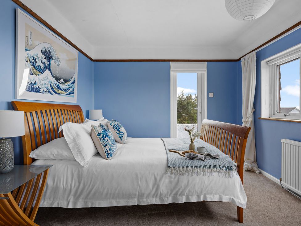 A bedroom with a bed and art on the wall at 7 Duporth Bay in St. Austell