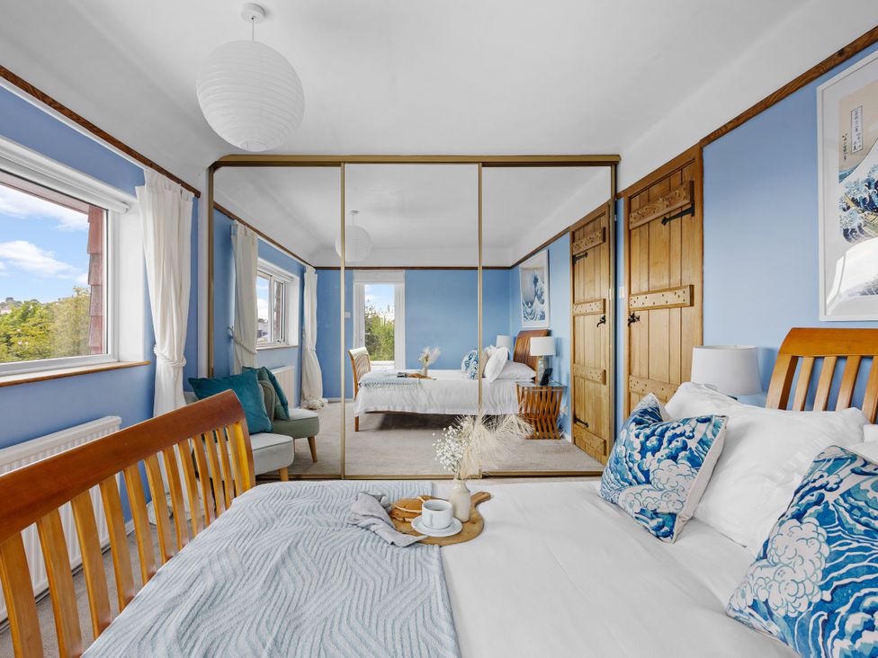 A bedroom with a bed, wardrobe, and table at 7 Duporth Bay in St. Austell