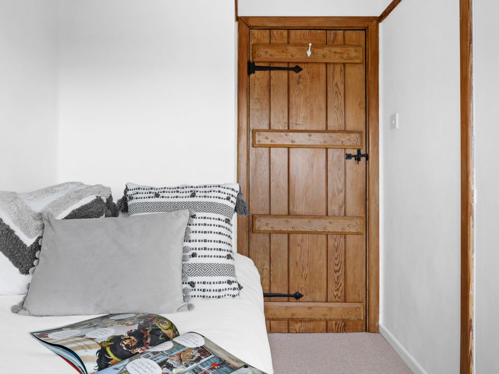 A bedroom with a bed and wooden door at 7 Duporth Bay in St. Austell