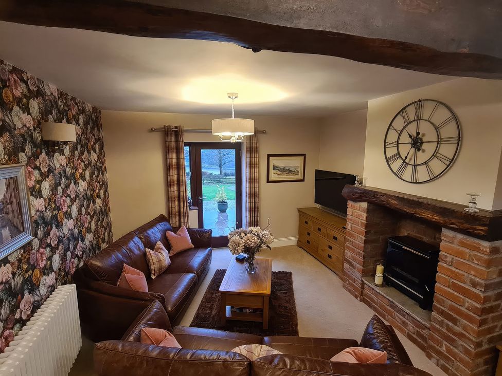 A living room with a fireplace and television at Dairy Cottage in Thornton in Lonsdale near Ingleton