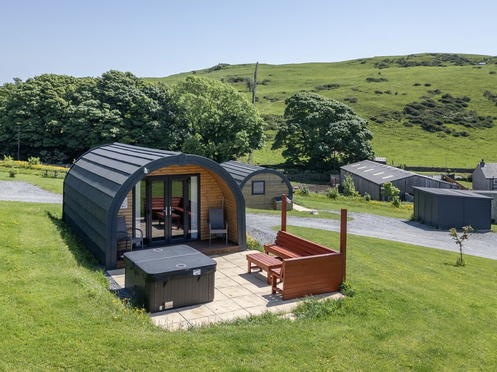 A pod with a deck and hot tub in a grassy area at Beech in Ulverston