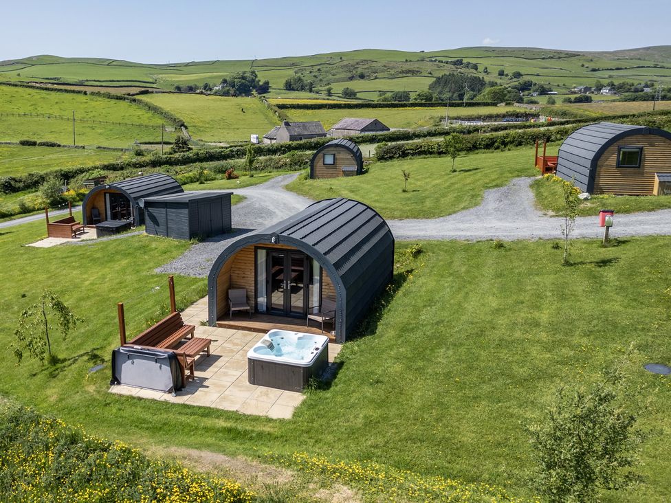 An outdoor area with glamping pods and a hot tub at Beech in Ulverston