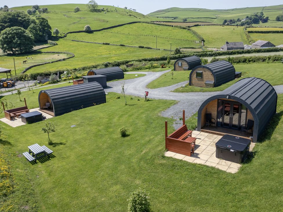 An outdoor area with glamping pods and a hot tub at Beech in Ulverston