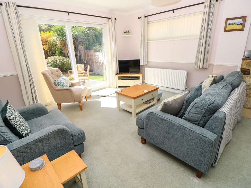 A living room with a sofa, armchair, coffee table and television at Altair in Colwell Bay near Freshwater