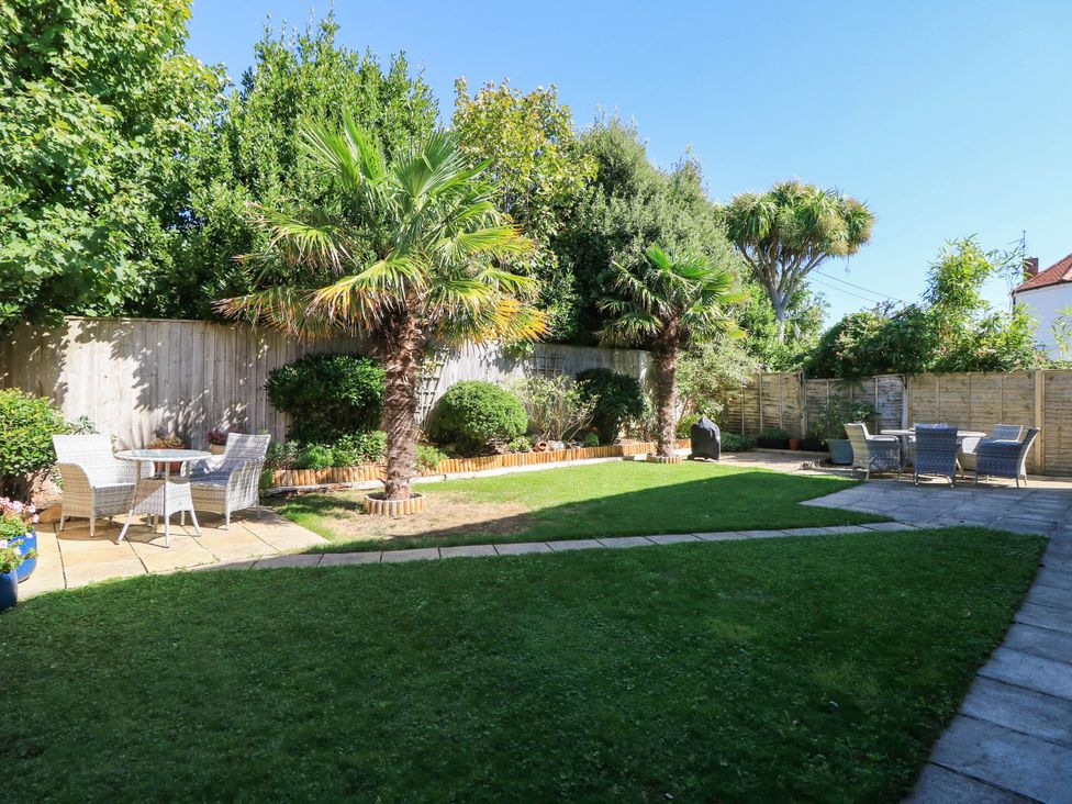 A garden with palm trees and seating areas at Altair in Colwell Bay near Freshwater