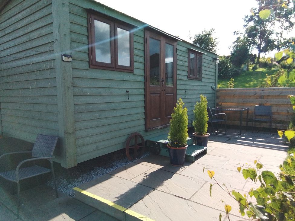 A shepherd's hut with a patio and planters at The Herdsman Luxury Shepherds Hut in Barnoldswick