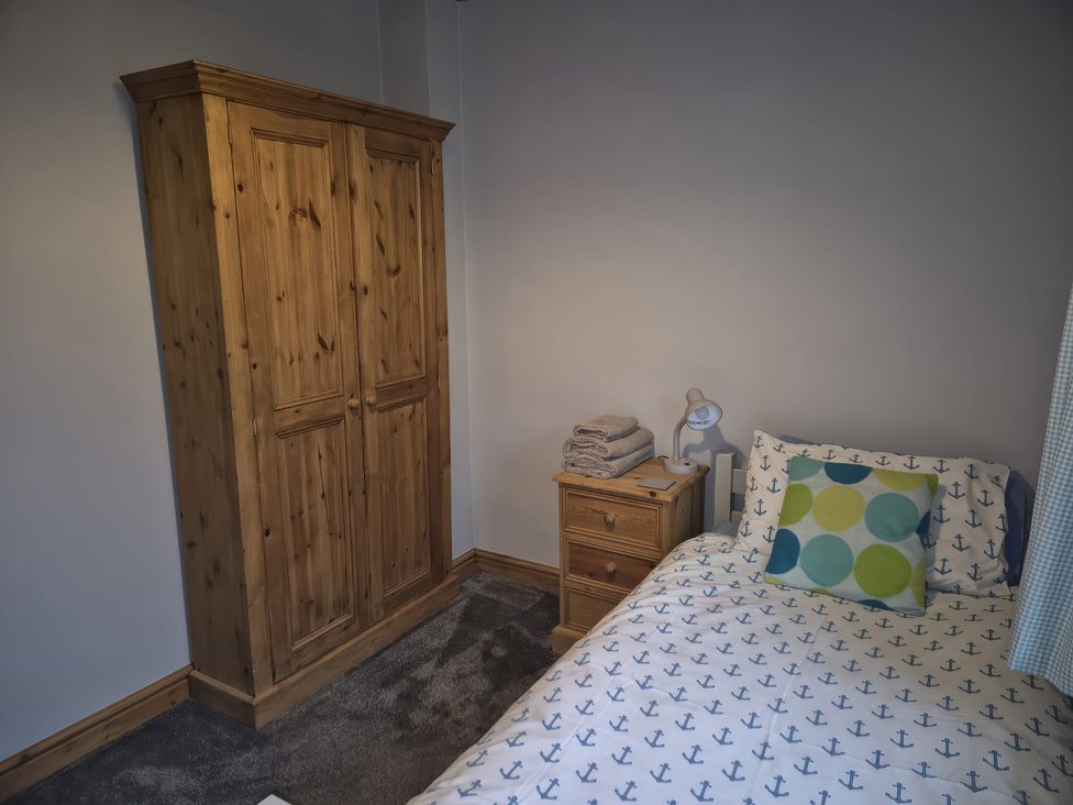 A bedroom with a bed and wardrobe at Ty Gwenyn in Rhydwyn