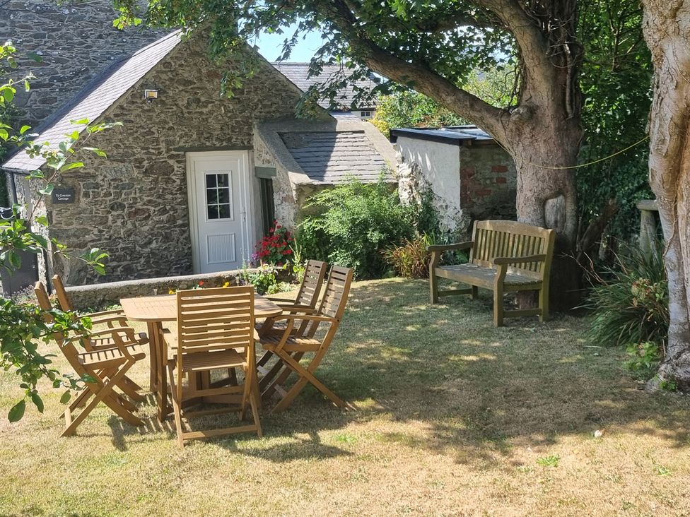 A garden with a table and chairs beside a house at Ty Gwenyn in Rhydwyn