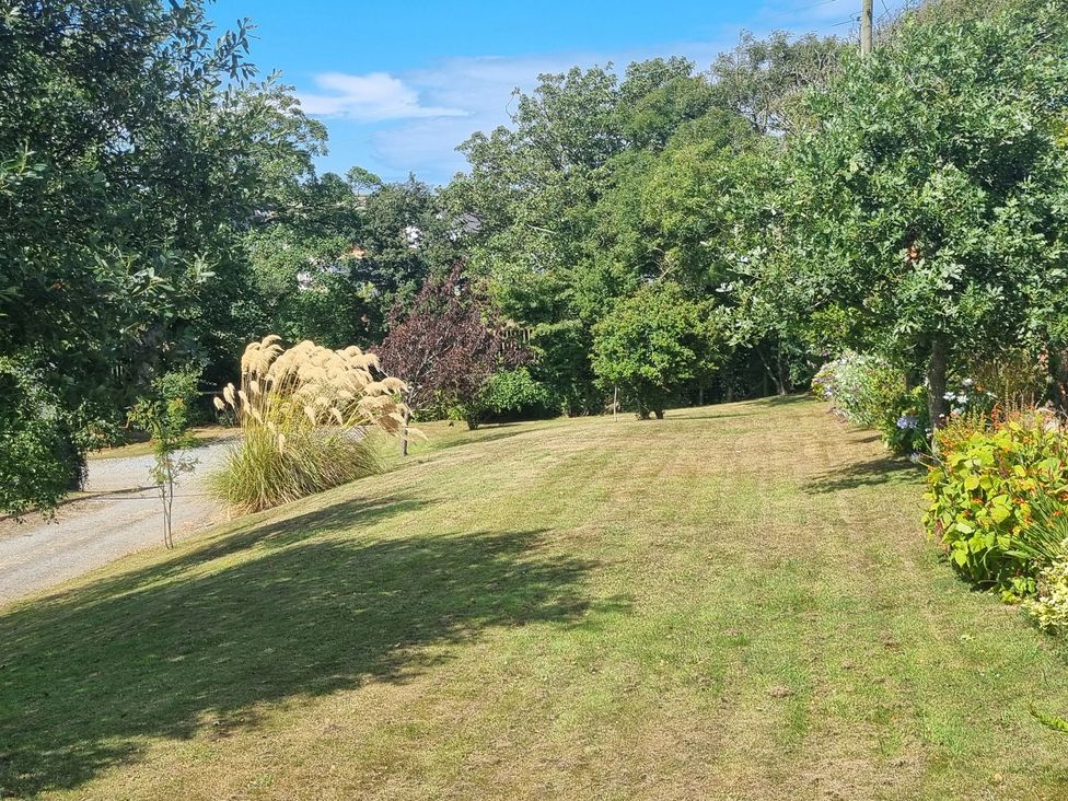 A garden with grass and trees at Ty Gwenyn in Rhydwyn
