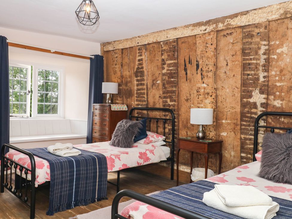 A bedroom with two beds and a wooden wall at The Abbey Grange near Charmouth