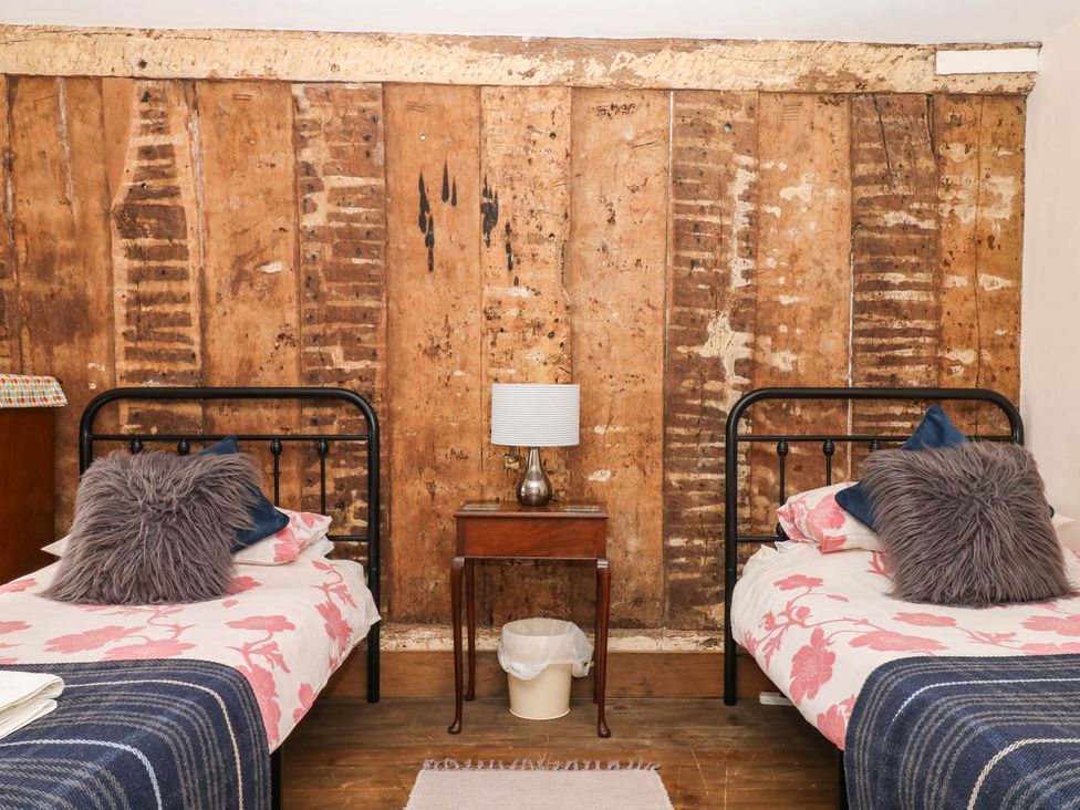 A bedroom with two beds and a lamp on a side table at The Abbey Grange near Charmouth