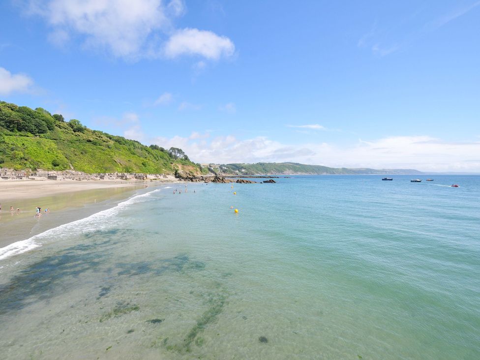 A beach with people swimming and boats in the water at The Abbey Grange near Charmouth