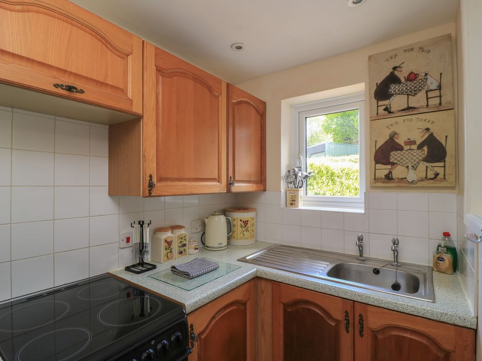 A kitchen with cabinets, stove, sink, and window at Ryecross Farm Cottage in Shaftesbury