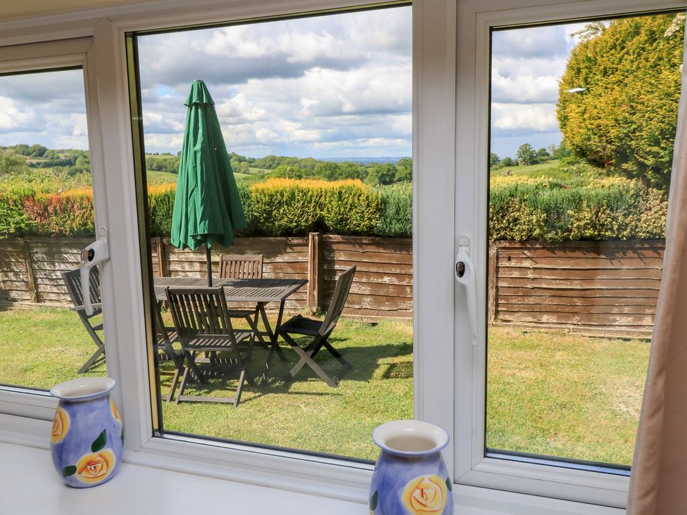 A view of a garden with a table and chairs from a window at Ryecross Farm Cottage in Shaftesbury