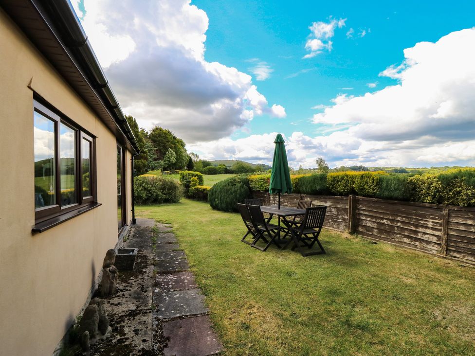A garden with a table and chairs under an umbrella at Ryecross Farm Cottage in Shaftesbury
