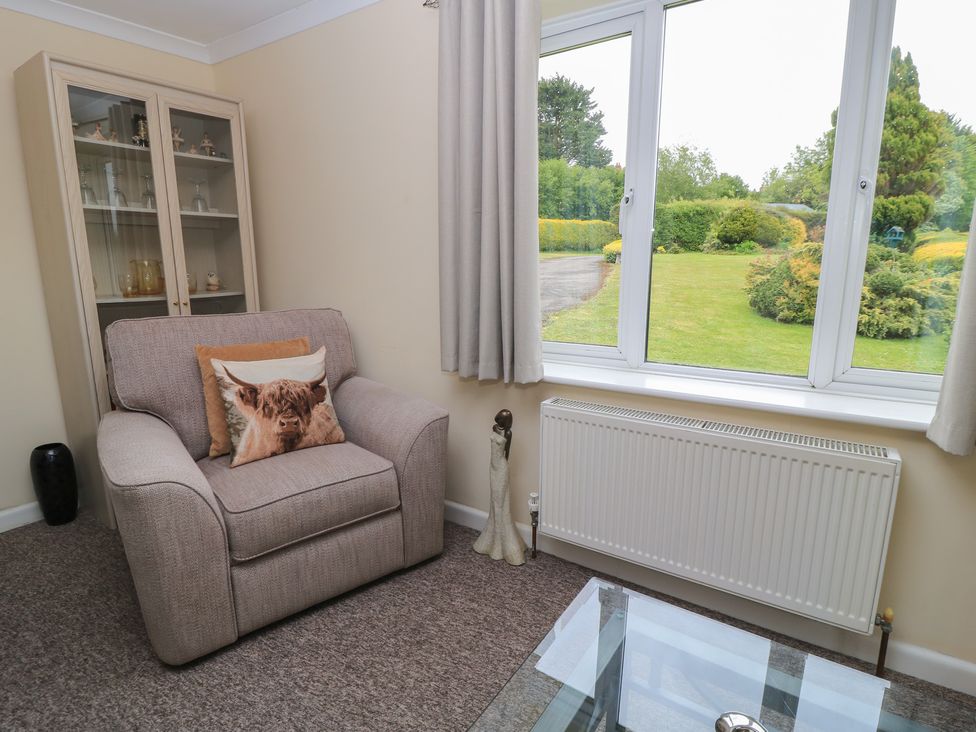 A living room with an armchair and a glass table at Ryecross Farm Cottage in Shaftesbury