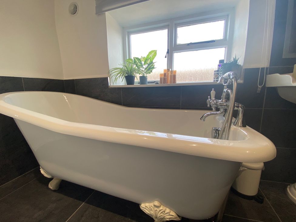 A bathroom with a bathtub and window at The Hollies Thurstonfield near Carlisle