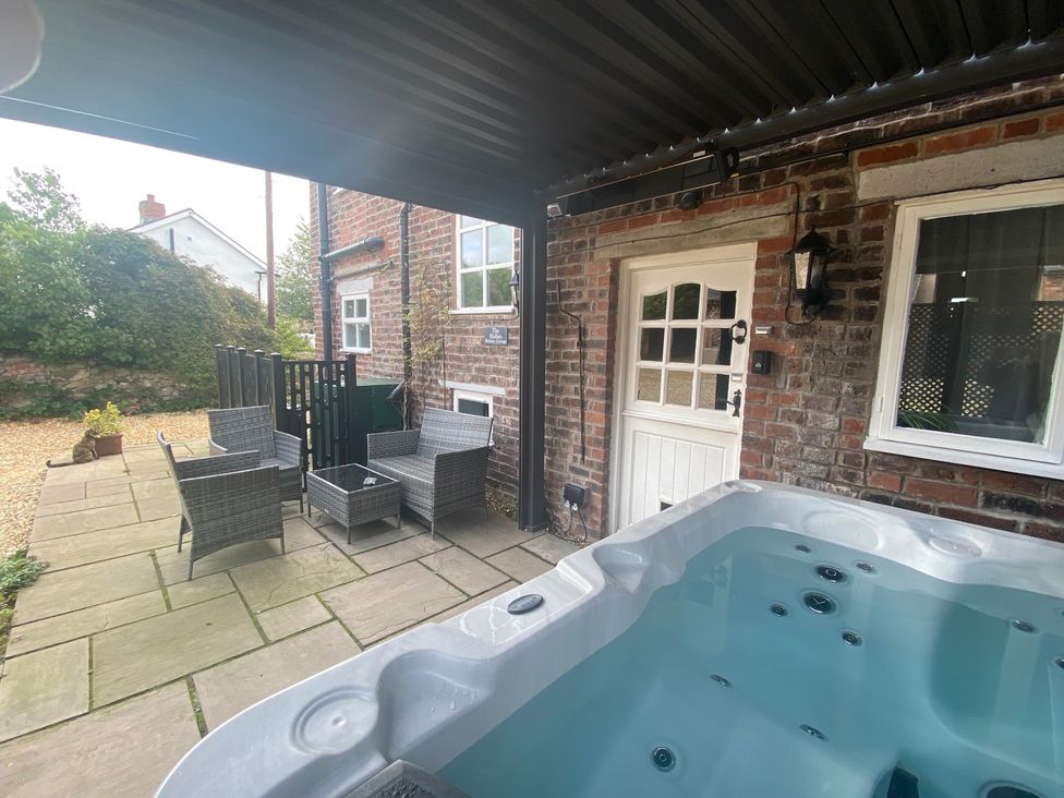 An outdoor patio with a hot tub and seating area at The Hollies in Thurstonfield near Carlisle