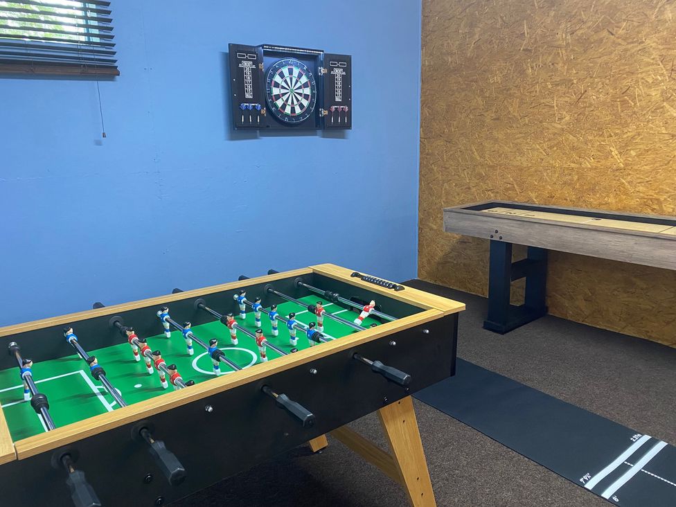 A game room with a foosball table and dartboard at The Hollies in Thurstonfield near Carlisle
