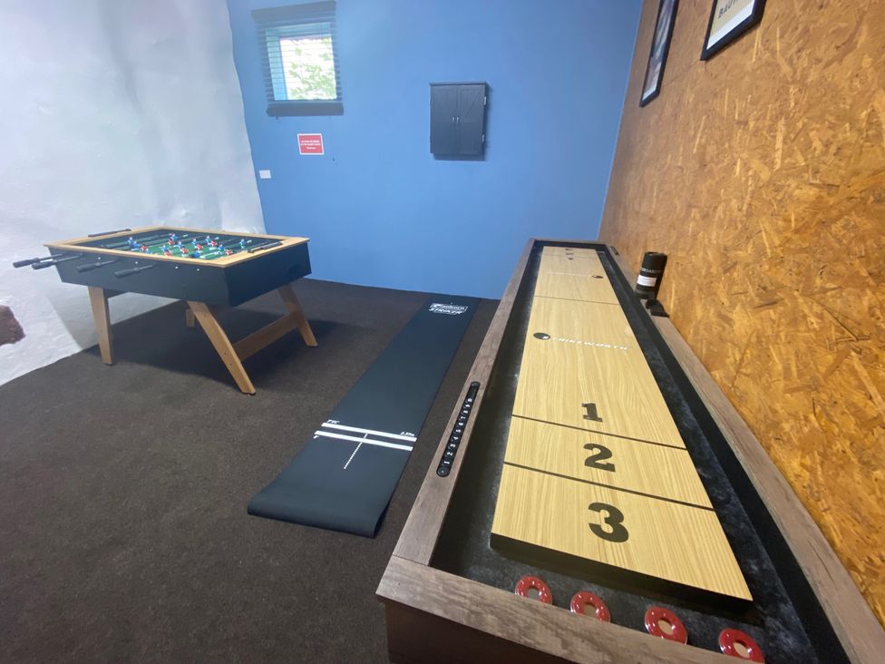 A game room with a foosball table and a shuffleboard table at The Hollies in Thurstonfield near Carlisle