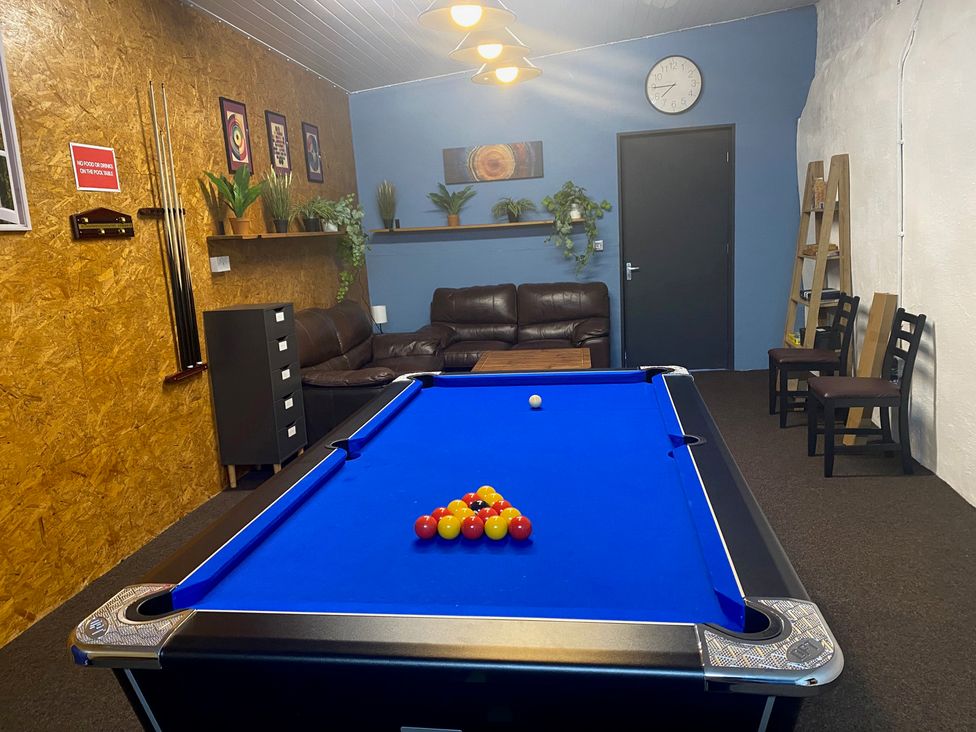A game room with a pool table and a sofa at The Hollies in Thurstonfield near Carlisle