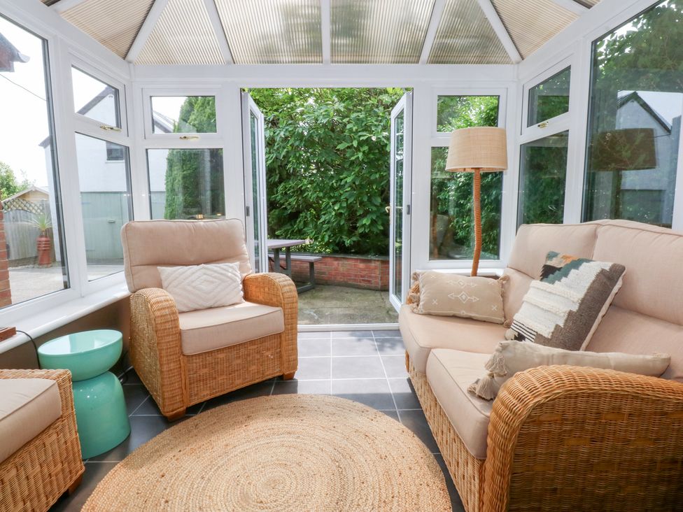 A conservatory with seating and access to the garden at Fairfield in Llanbedrog