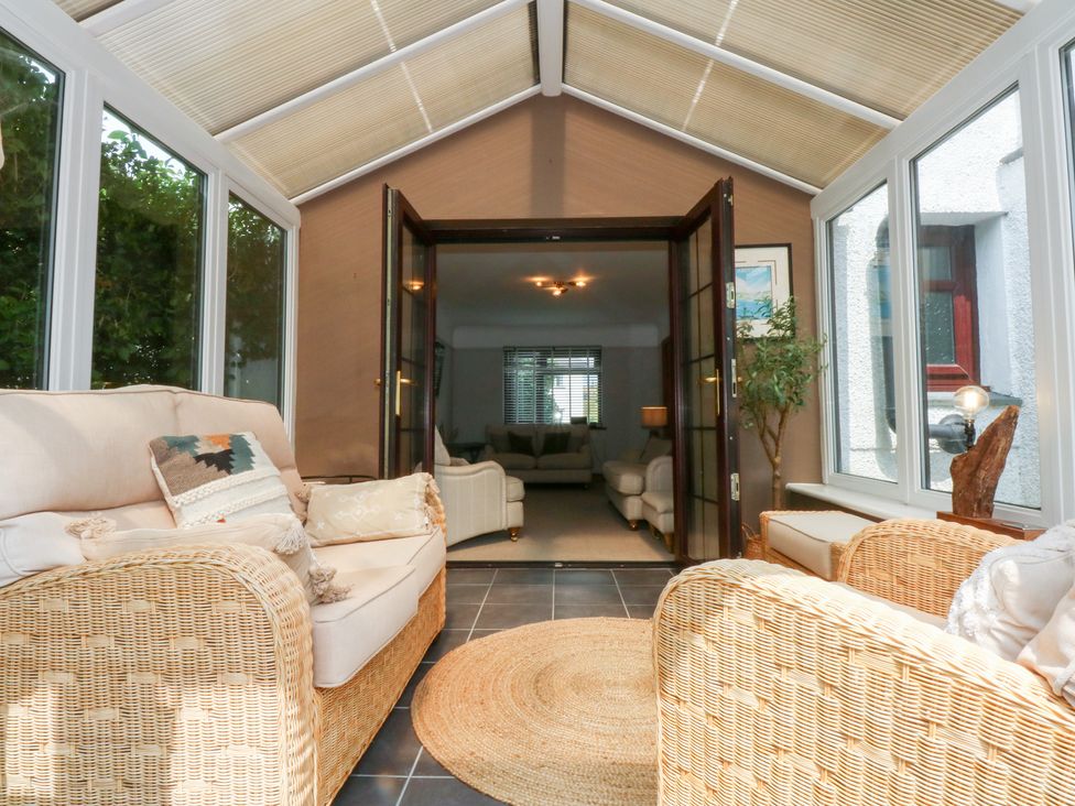 A conservatory with sofas and plants at Fairfield in Llanbedrog