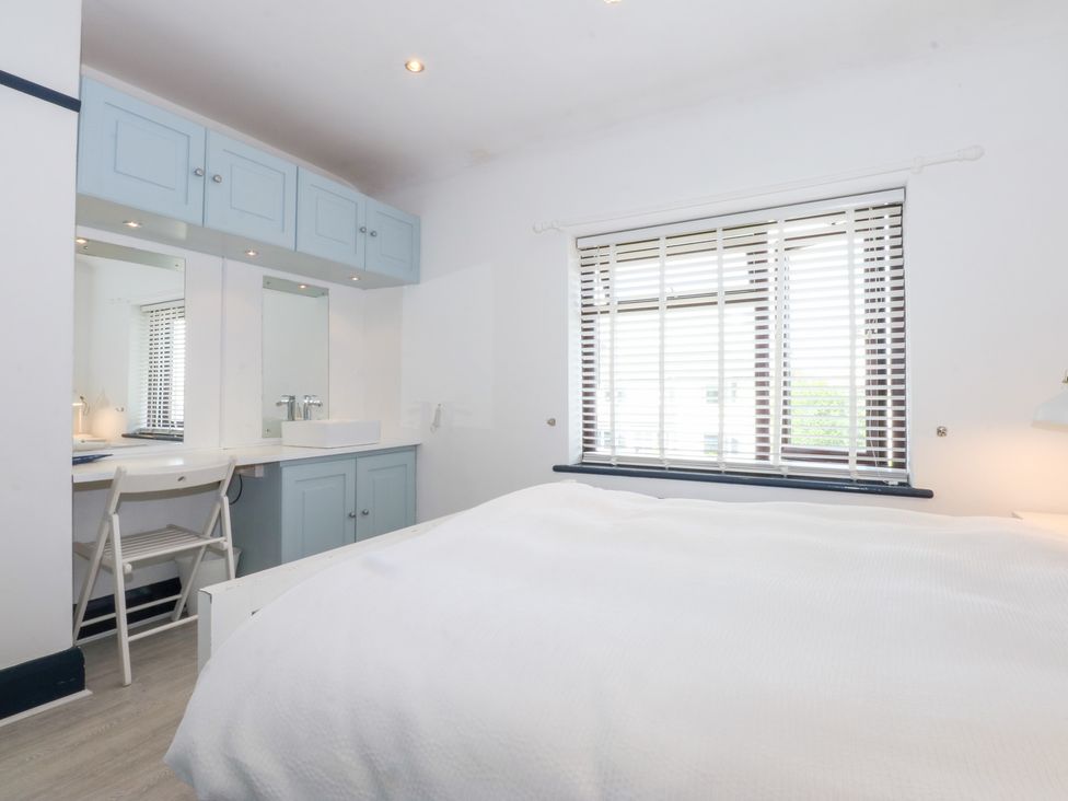 A bedroom with a bed, dresser, and windows at Fairfield in Llanbedrog
