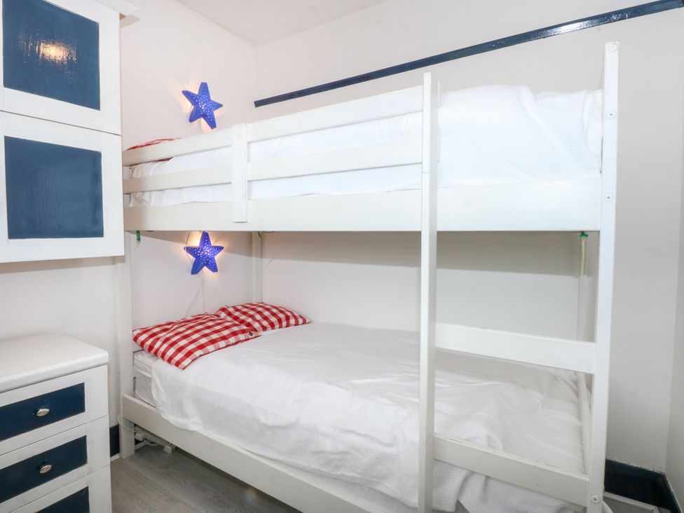 A bunk bed with red checkered pillows in a bedroom at Fairfield Llanbedrog