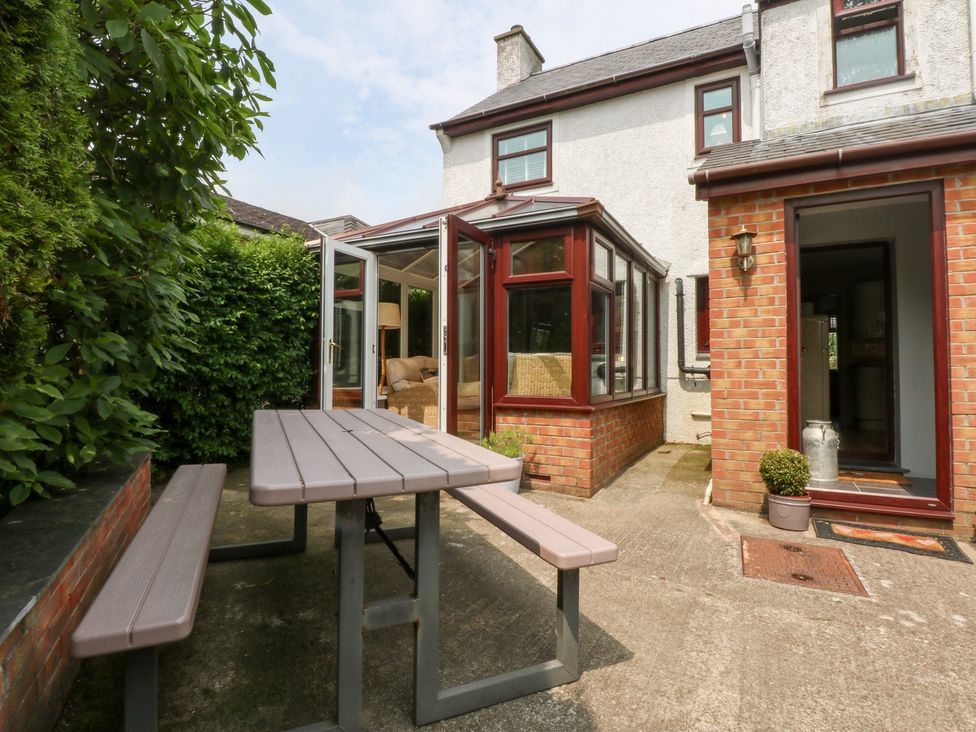 A table and chairs in a garden near a conservatory at Fairfield in Llanbedrog