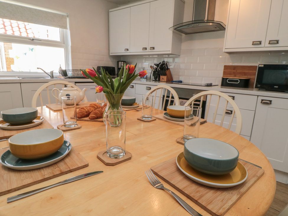A dining table set with plates and glasses at Bluebell Cottage Flamborough