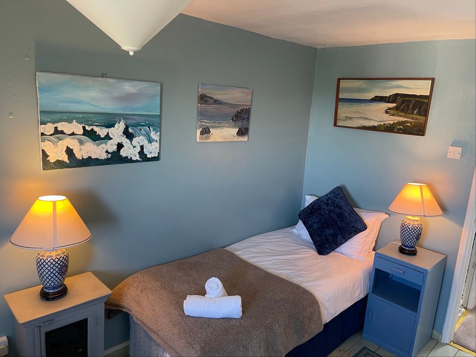 A bedroom with a single bed and paintings on the wall at 11 Penygroes in Llanddeusant