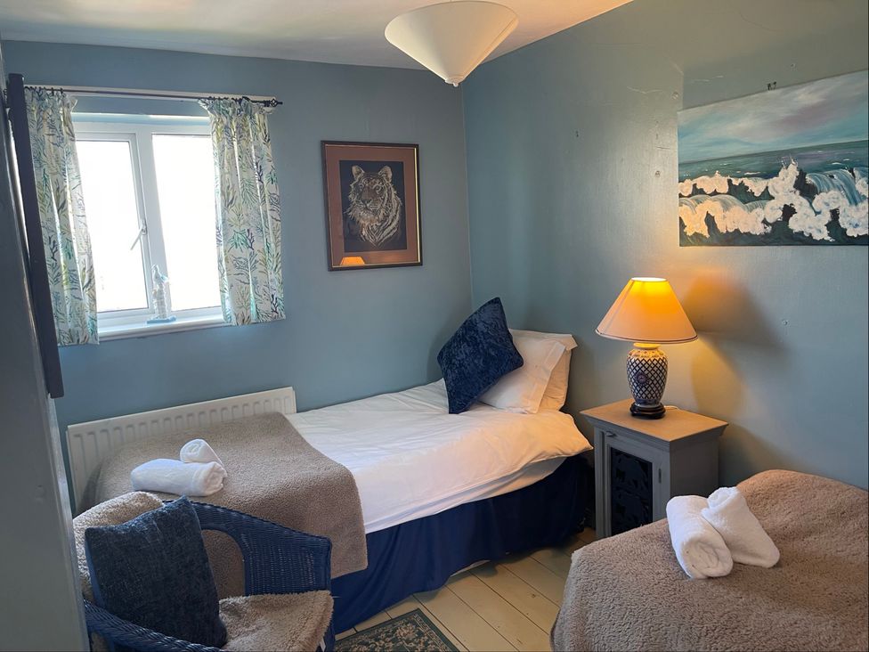 A bedroom with two beds and a lamp on a nightstand at 11 Penygroes in Llanddeusant
