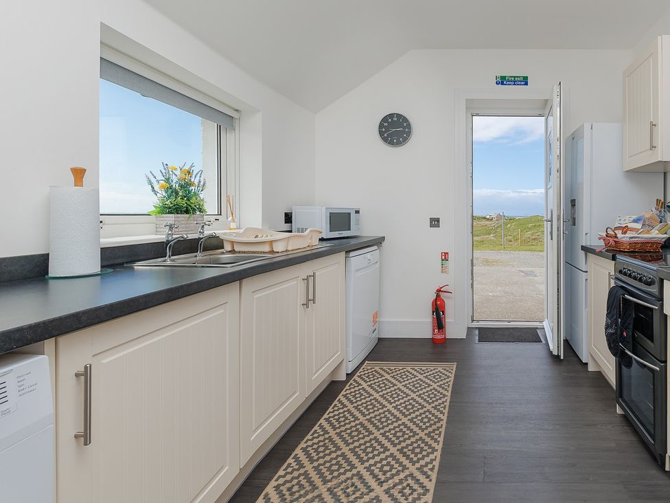 A kitchen with appliances and a door leading outside at Dun Buidhe South Boisdale near Daliburgh Isle Of South Uist