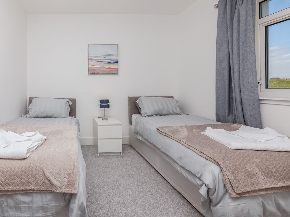 A bedroom with two beds and a bedside table at Dun Buidhe South Boisdale near Daliburgh Isle Of South Uist