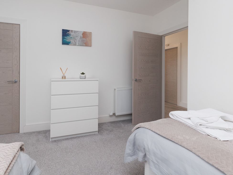A bedroom with a dresser and wall art at Dun Buidhe South Boisdale near Daliburgh Isle Of South Uist