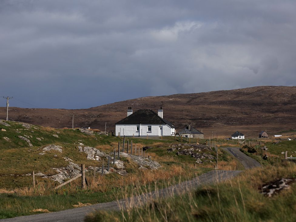 A house beside a road with hills in the background at Dun Buidhe in South Boisdale near Daliburgh, Isle Of South Uist