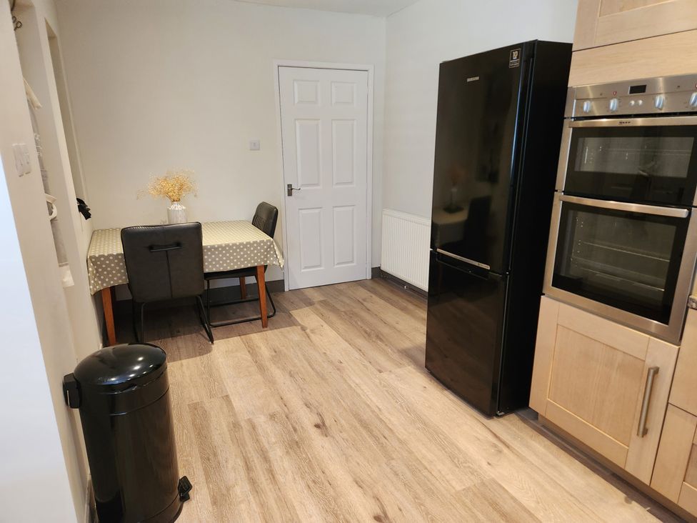 A kitchen with a table and chairs and appliances at 8 Arvonia Terrace Cricieth