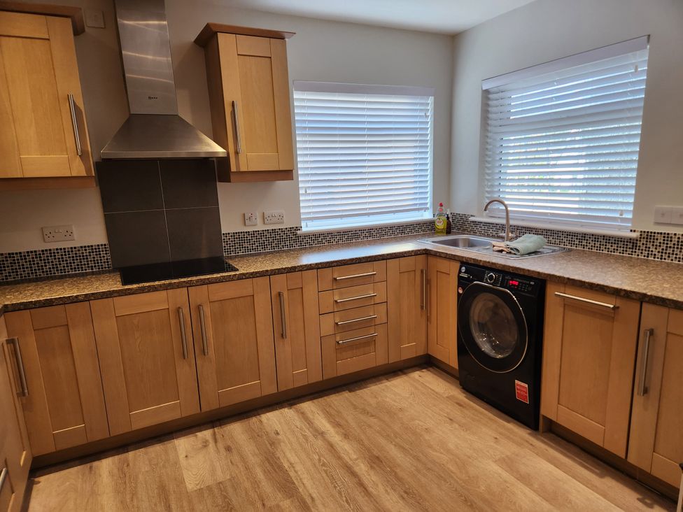 A kitchen with cabinets, sink, and washing machine at 8 Arvonia Terrace Cricieth